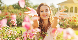 Joyful woman throwing petals out in front of her while outdoors in the sun smiling